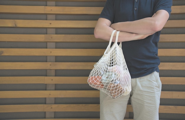 man holding a mesh bag with products without plastic packaging