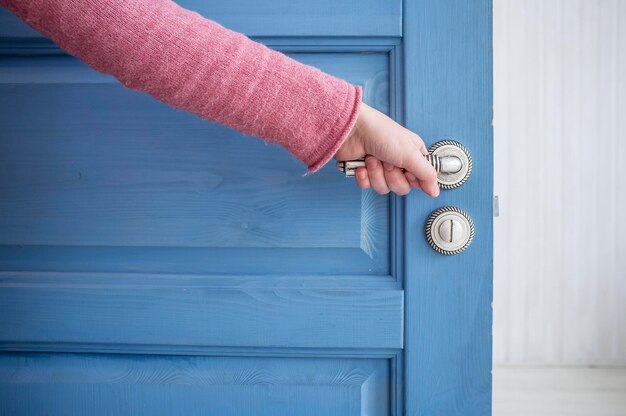 Man holding a metal pen in an open wooden door blue