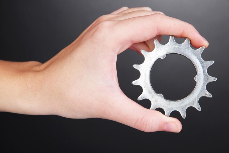 Photo man holding metallic cogwheel in his hand on gray background
