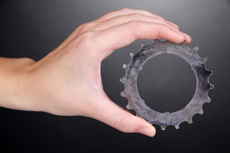 Photo man holding metallic cogwheel in his hand on gray background