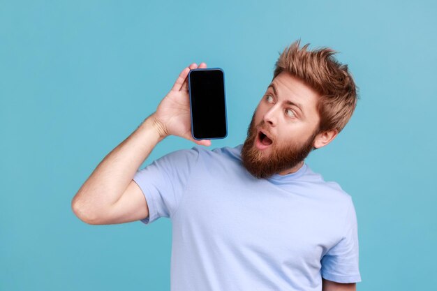 Man holding mobile phone looking in surprise at gadget display with empty space modern technology