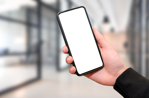 Man holding mobile phone with empty blank screen in hand at the office