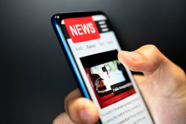 Photo a man holding mobile smart phone with news on screen newspaper online portal in browser