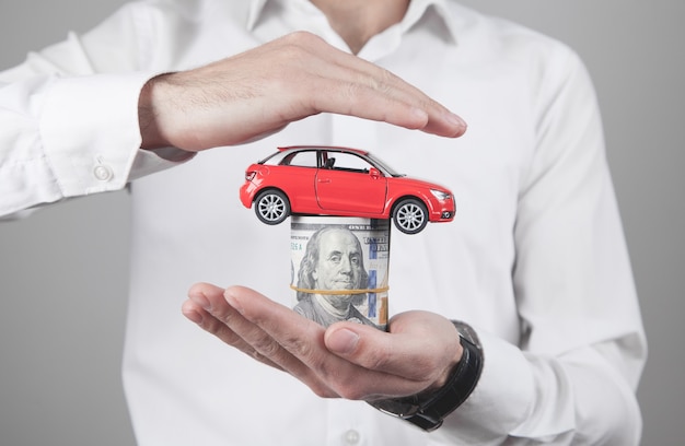 Man holding money and red toy car.
