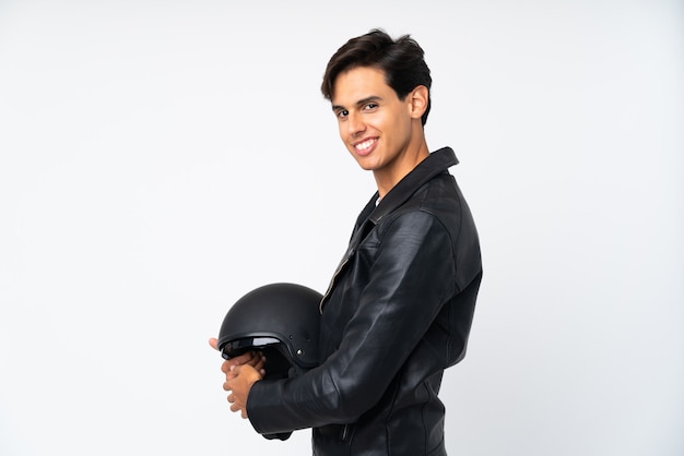 Мужчина держит мотоциклетный шлем над белой смеющейся стеной