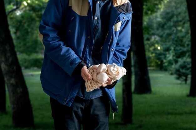 A man holding mushrooms in the forest . gather mushrooms season