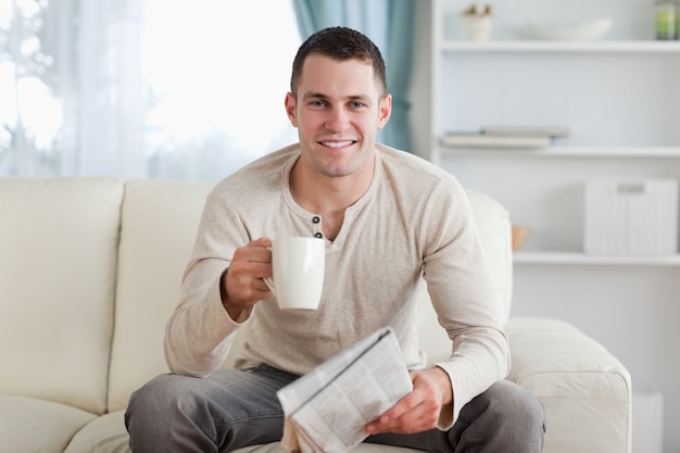 紅茶を飲みながら新聞を持っている男