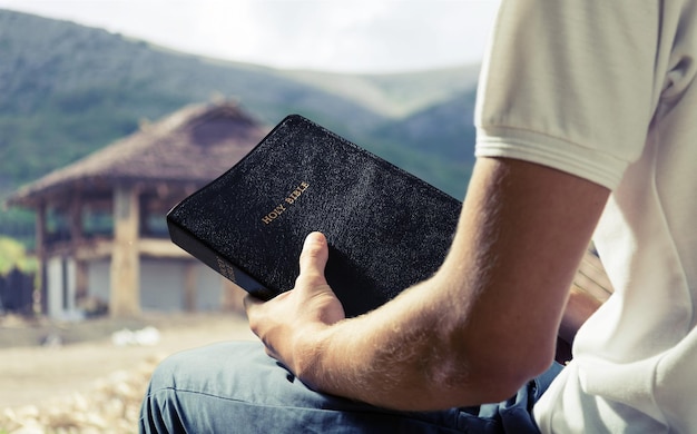 写真 背景に古い聖書の本を持っている男