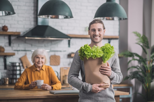 Man holding a package of greens in his hands