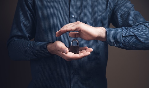 A man holding a padlock in his hands in the form of protection on a brown surface