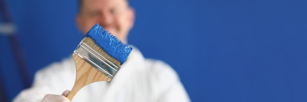 Foto uomo che tiene il pennello con il primo piano di vernice blu