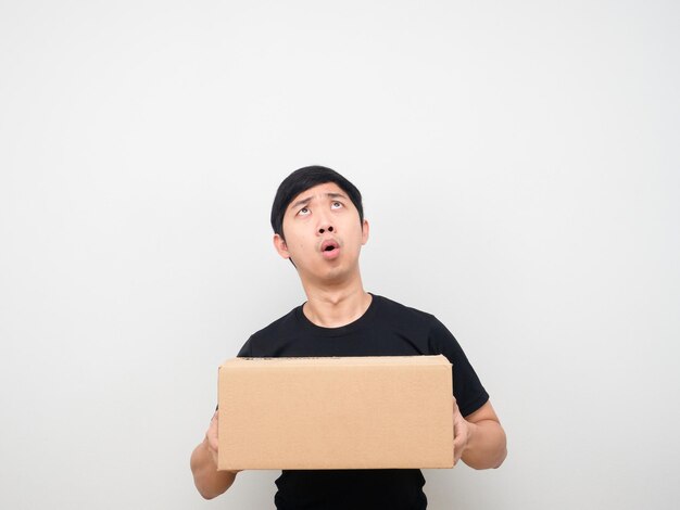 Man holding parcel box feeling amazed looking up at copy space