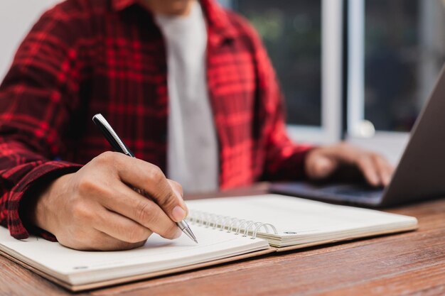 Man holding a pen sitting on a desk writing