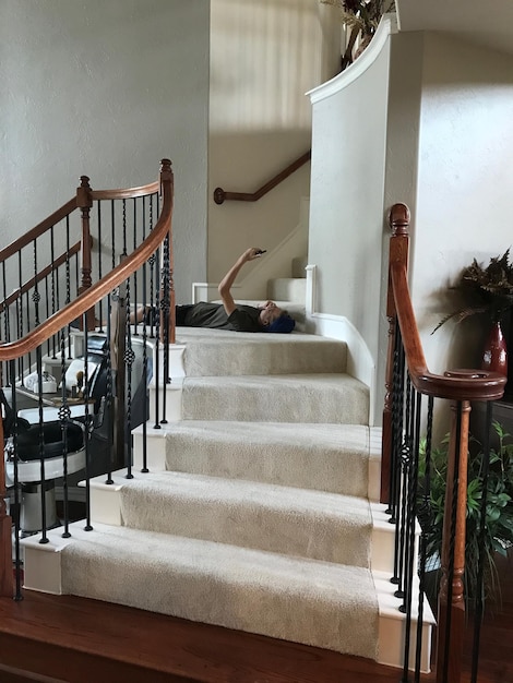 Man holding phone while lying down on steps at home