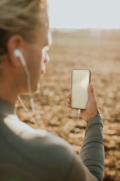 空の画面とデザインスペースで携帯電話を保持している男