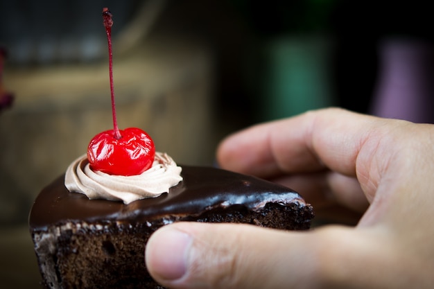 Man holding piece of delicious chocolate cake, closeup.