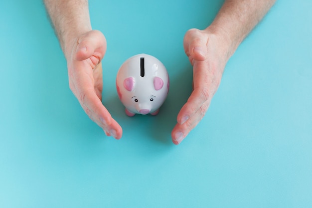 Man holding piggy bank on blue background