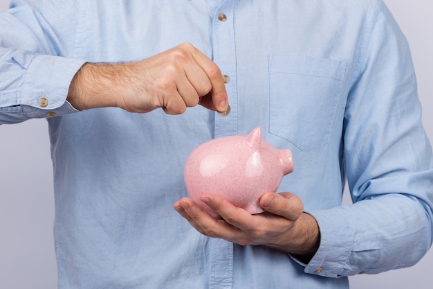 Man holding piggy Bank and puts in her coin. save money, savings concept.