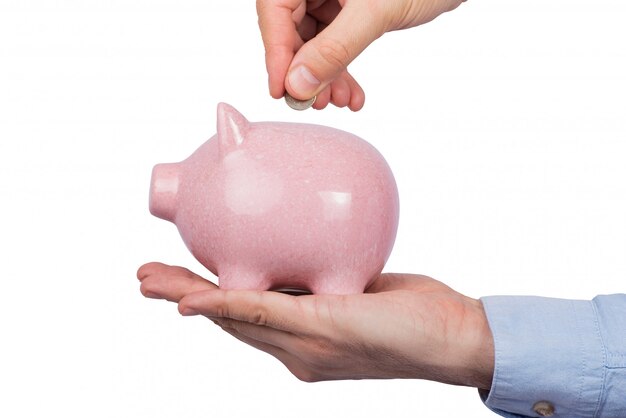 Man holding piggy Bank and throws coins. White background. Savings concept.