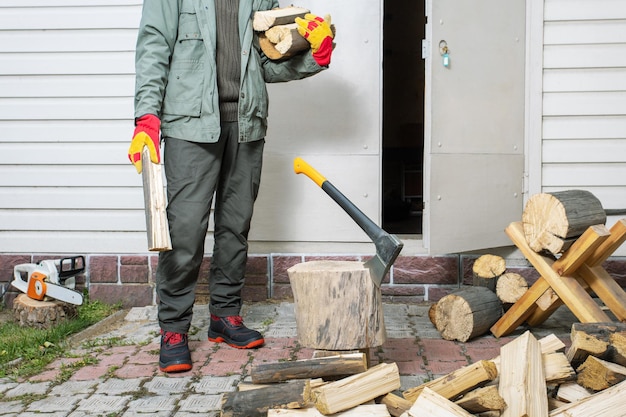 Мужчина держит кучу рубленого дерева Концепция подготовки дров для отопления дома