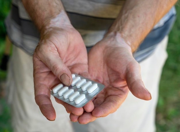 手に錠剤の山を持っている男