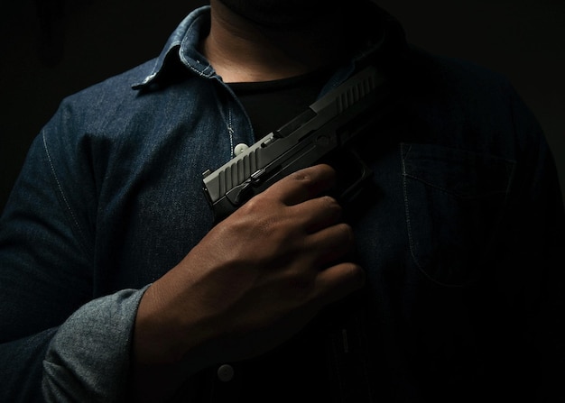 Man holding a pistol standing in a room in blackconcept of assassination murder criminal