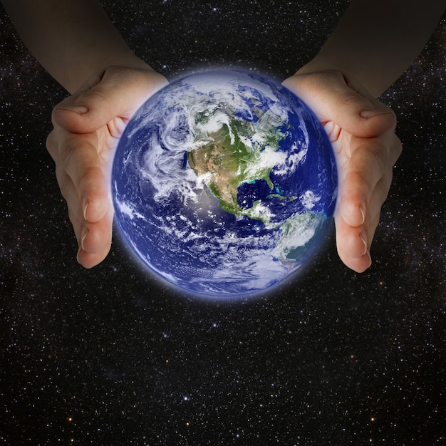 Man holding the planet earth in the hands against the wall of the galaxy.