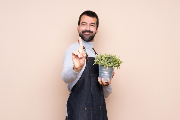 Man holding a plant showing and lifting a finger