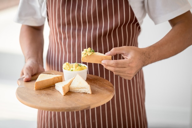 蜂蜜とチーズとトーストのプレートを持っている男