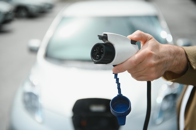 Man holding power connector for electric car