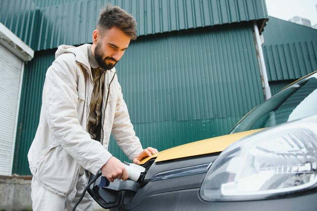 Man holding power connector for electric car