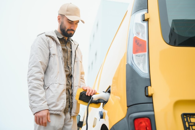 Uomo che tiene il connettore di alimentazione per auto elettrica