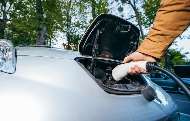 Man holding power supply cable at electric vehicle charging station Closeup