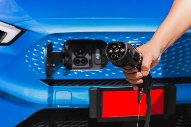 Man holding power supply cable at electric vehicle charging station