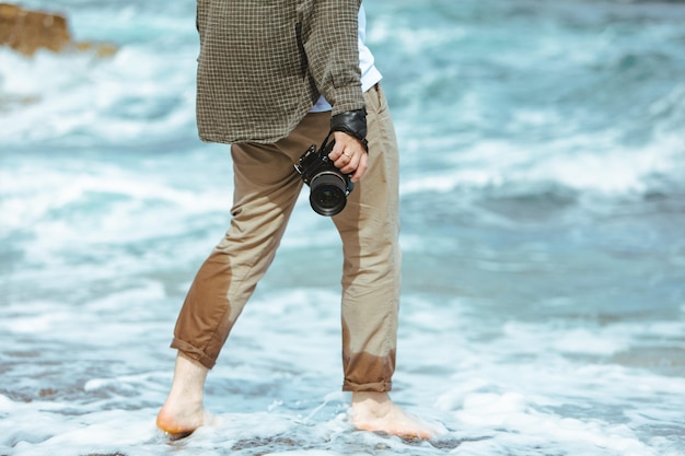 Man holding professional came in hand walking by sea beach