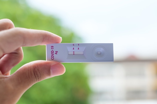 Photo man holding rapid antigen test kit with negative result during swab covid-19 testing. coronavirus self nasal or home test, lockdown and home isolation concept