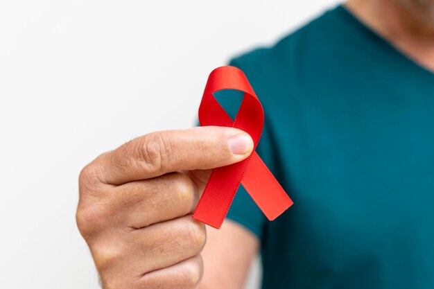 Man holding red AIDS awareness ribbon World Aids Day and World Diabetes Day Prevention concept