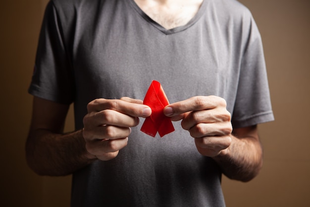 A man holding a red aids ribbon