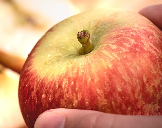 a man holding a red apple with his hand in macro photography