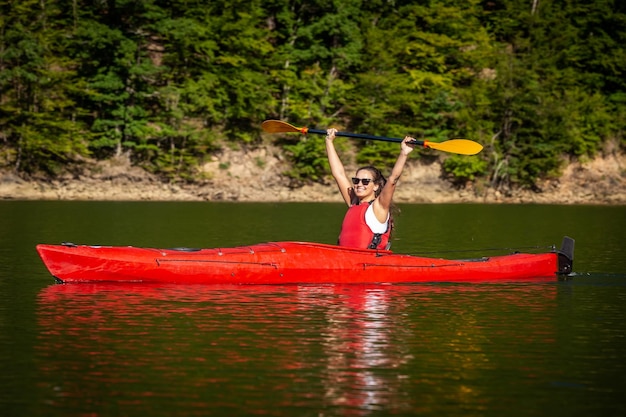 Foto uomo che tiene una barca rossa nel lago contro gli alberi