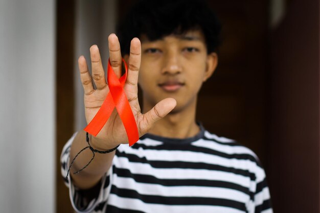 Man holding red ribbon showing support for AIDS Awareness