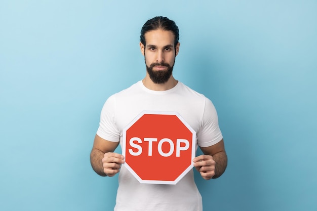 Man holding red stop sign looking at camera with negative aggressive expression showing ban