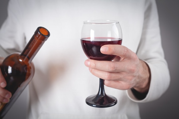 Man holding red wine bottle and glass.