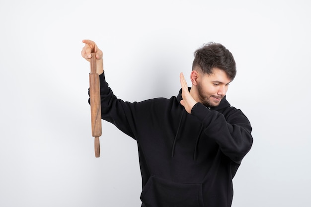 Man holding rolling pin in hand and standing against white background