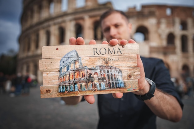 Photo man holding rome colosseum souvenir colosseum in background