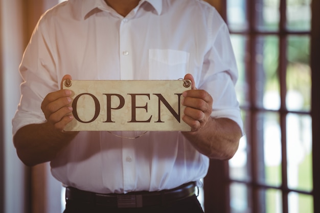 Photo man holding a sign with open