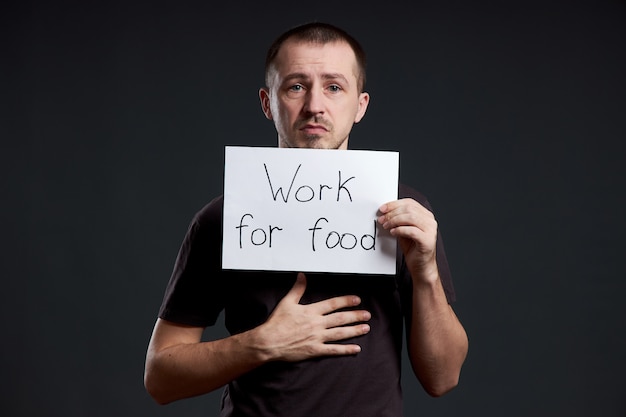 Man holding a sign with the words work for food