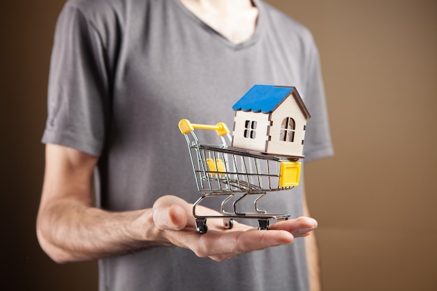 A man holding a small basket with a small house on a brown background