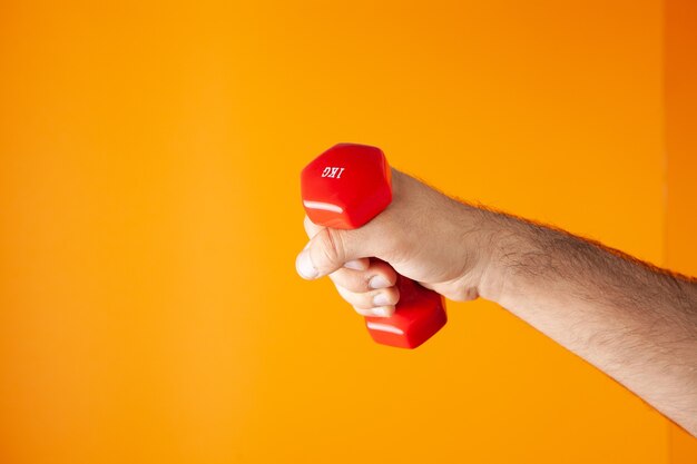 Man holding small dumbbells on orange background