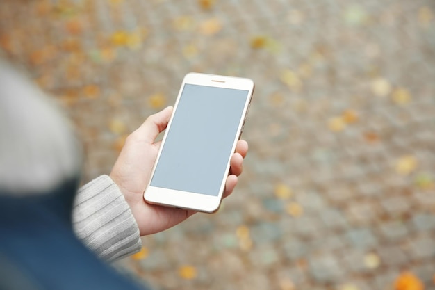 Man holding smart phone on blurred paving stone background